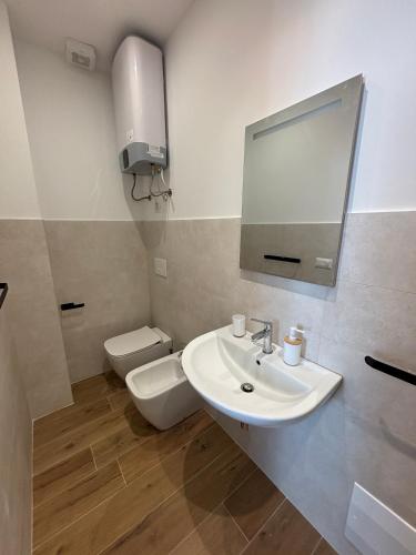 a bathroom with a sink and a toilet and a mirror at MARIS Apartments & Bedrooms in Alghero