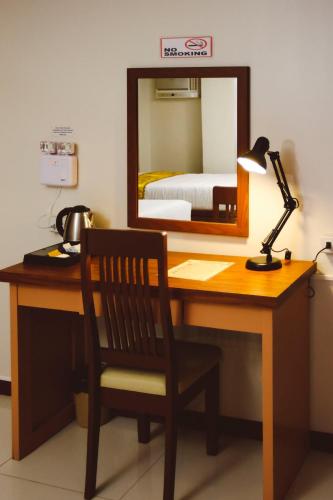 a desk with a lamp and a mirror and a bed at Surigao Royal Regency Suites in Surigao