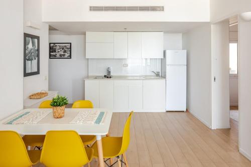 a kitchen and dining room with a table and yellow chairs at Trumpeldor 1 - Luxury Beach Apartments Hotel - By Vacay in Tel Aviv