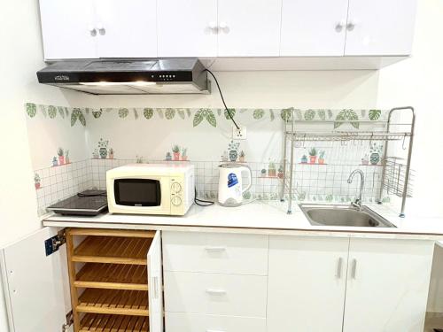 a white kitchen with a microwave and a sink at Beautiful Hotel Vinhomes Grand Park - Long Bình in Gò Công