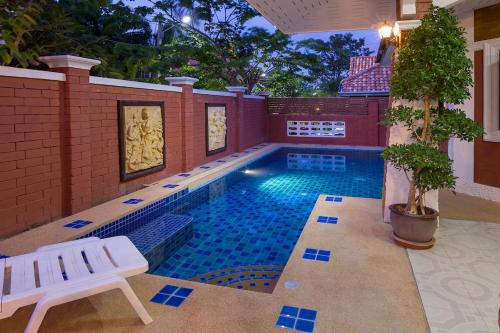 a swimming pool with a bench next to a house at Villa Marcello in Pattaya South