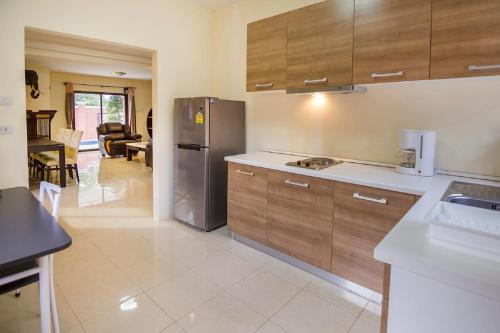a kitchen with wooden cabinets and a stainless steel refrigerator at Villa Marcello in Pattaya South