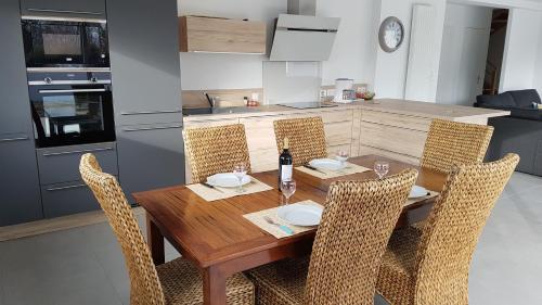 - une table à manger avec des chaises et une bouteille de vin dans l'établissement Maison neuve 400 m des plus belles plages, à Loctudy