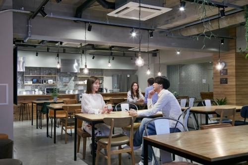 a group of people sitting at tables in a restaurant at GRAND HOSTEL LDK Osaka Shinsaibashi in Osaka