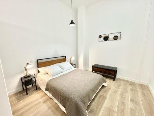 a white bedroom with a bed and a night stand at Renfe Asamblea de Madrid 01 AMCH Hospedaje in Madrid