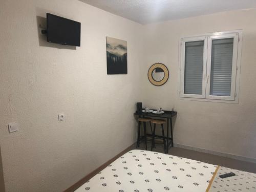 a bedroom with a bed and a table and a television at Le Manteau Bleu in Béziers