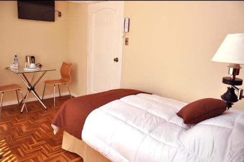 a bedroom with a bed with a table and a chair at Bolivian Rooms & Suites (Zona Sur) in La Paz