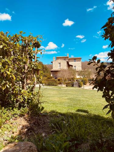 an old building in the distance with a grass field at Re Artù Assisi Country Lifestyle in Assisi