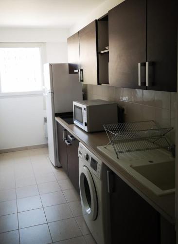 une cuisine avec un lave-linge et un micro-ondes dans l'établissement Appartement cosy sur la French Riviera, à Nice