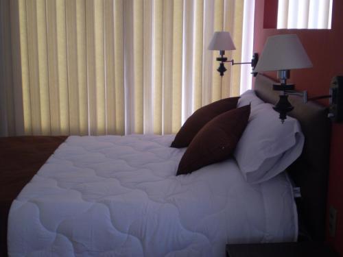 a bed with white sheets and pillows in a bedroom at Bolivian Rooms & Suites (Zona Sur) in La Paz