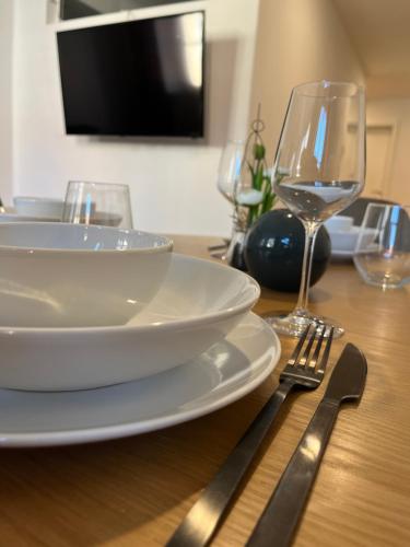 a wooden table with a white plate and wine glasses at traumhafte Business & Relax Wohnung direkt im Stadtkern Oettingens by Elation Homes in Oettingen in Bayern