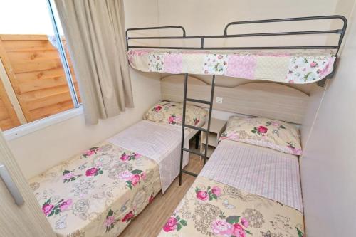 two bunk beds in a small room with a window at Mobillehome Camp Turanj in Turanj