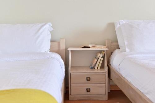 a bedroom with two beds and a night stand with a book at Pharos Rooms in Ilia