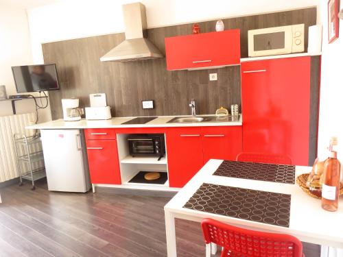 a red kitchen with a sink and a red cabinets at Le petit gîte de la tour in Montoulieu