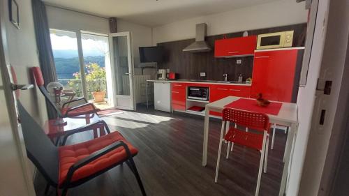 a kitchen with red cabinets and a red table and chairs at Le petit gîte de la tour in Montoulieu