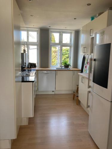a kitchen with white cabinets and a wooden floor at Charmerende byhus - tæt på alt! in Svendborg