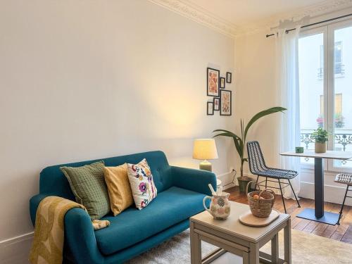 un salon avec un canapé bleu et une table dans l'établissement Parisien Élégant & Calme, à Paris