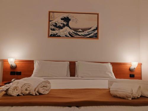 a bedroom with a bed with a painting of the wave at Niji Hotel&Restaurant in Mapello