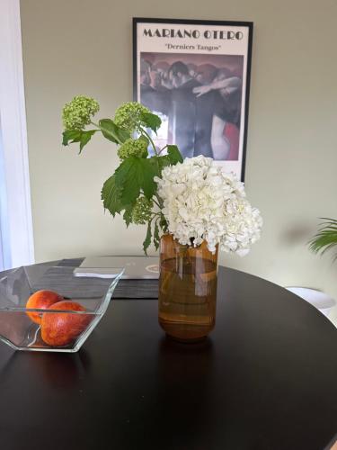 un vase avec des fleurs et un bol de fruits sur une table dans l'établissement Val es Roses, à Dinard