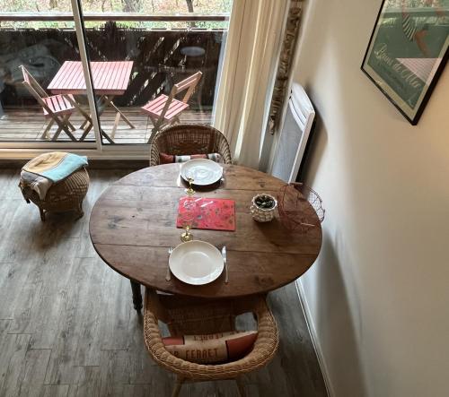 Cette chambre dispose d'un balcon avec une table et des chaises en bois. dans l'établissement Séjour nature et détente dans la pinède, à Lège-Cap-Ferret