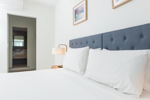 a bedroom with a large white bed with a blue headboard at Darwin Harbour Suites in Darwin