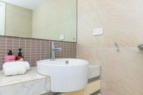 a bathroom with a white sink and a mirror at Darwin Harbour Suites in Darwin