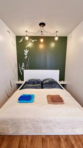 a bedroom with a white bed with a green wall at Rentoudu Tässä in Lahti