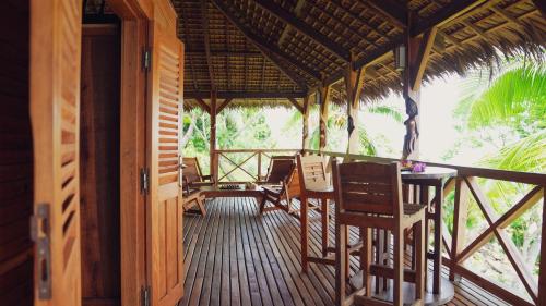a porch of a resort with chairs and a table at Manja Kely Lodge in Nosy Be