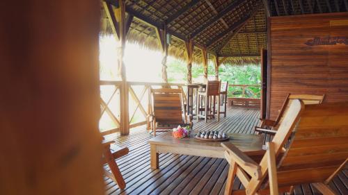 a porch of a hut with a table and chairs at Manja Kely Lodge in Nosy Be