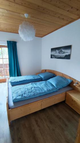 a bed in a bedroom with a wooden ceiling at FEWO Wimmer in Bischofswiesen