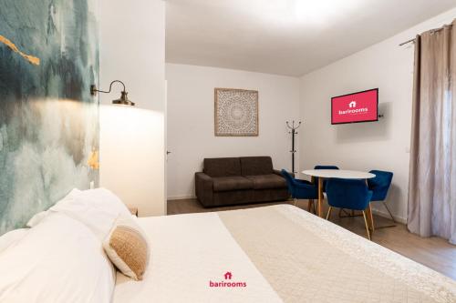 una camera da letto con un letto, un tavolo e un divano di BARIROOMS - Melo Suites a Bari