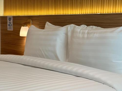 a bed with white pillows and a wooden headboard at Winston Hotel in Bangkok
