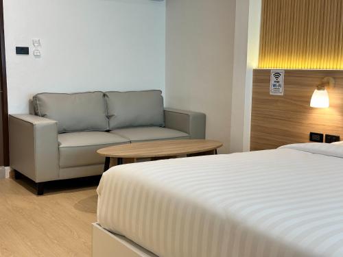 a room with a bed and a couch and a table at Winston Hotel in Bangkok