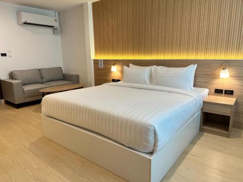 a bedroom with a large white bed and a couch at Winston Hotel in Bangkok
