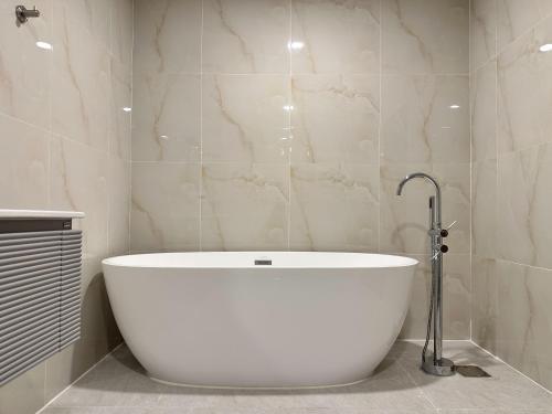 a large white bath tub in a bathroom at Winston Hotel in Bangkok