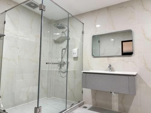 a bathroom with a glass shower and a sink at Winston Hotel in Bangkok
