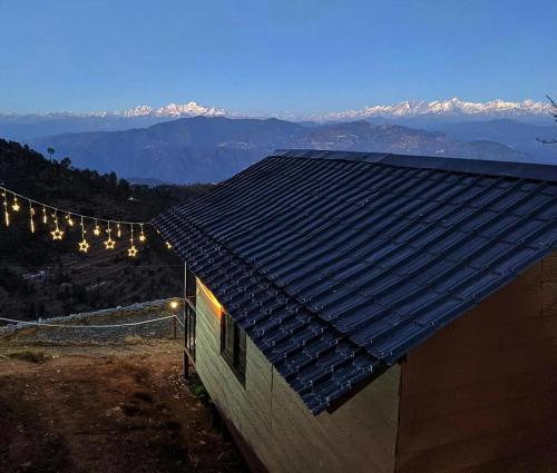 a house with lights on the side of a mountain at Navira Hills Kanatal in Kanatal