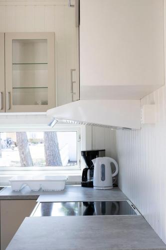 a kitchen with white cabinets and a tea kettle at Strandbyn - Destination Råbocka in Ängelholm