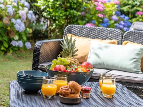 - une table avec un bol de fruits et des verres de jus d'orange dans l'établissement Charmant studio jardin bord de mer Carnac-Plage, à Carnac