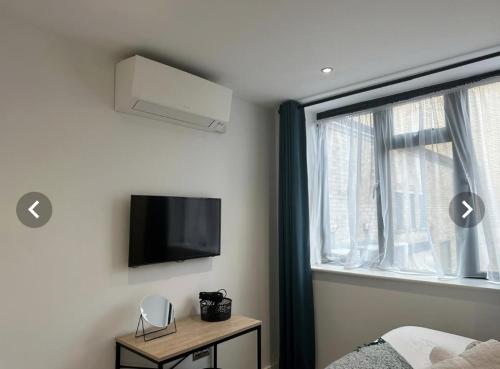 a bedroom with a bed and a tv and a window at City Centre Apartments - 1 Bed Apartments - 5 Min Walk from Train Station - Designed for Professionals - Free WiFi - Full Kitchen - Sofa Bed - Ideal for Long Work Stays in Peterborough