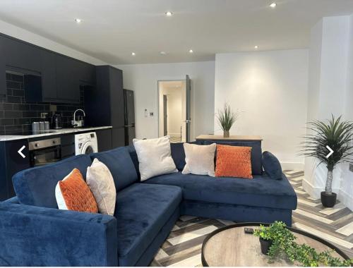 a living room with a blue couch with pillows at City Centre Apartments - 1 Bed Apartments - 5 Min Walk from Train Station - Designed for Professionals - Free WiFi - Full Kitchen - Sofa Bed - Ideal for Long Work Stays in Peterborough