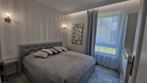 una camera da letto con un letto con cuscini e una finestra di Maxim Apartment Pobierowo a Pobierowo