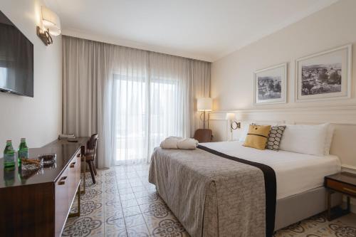 a hotel room with a bed and a large window at Edmond Luxury Hotel & Spa in Rosh Pinna