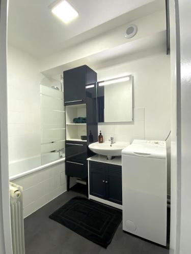 a white bathroom with a sink and a tub at L'Estrade, Studio centre-ville in Cholet