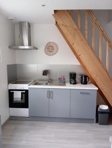 une cuisine avec des placards blancs et un escalier dans l'établissement La Petite Maison, à Ricarville-du-Val