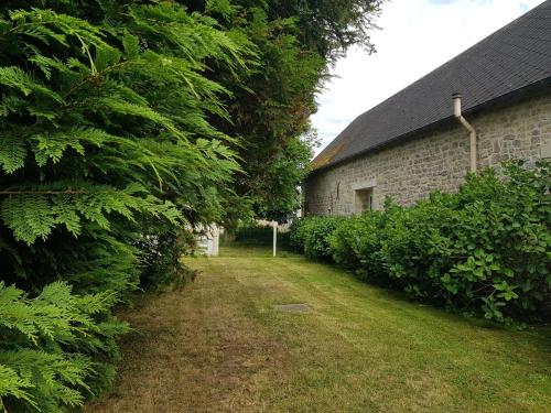 une cour à côté d'un bâtiment en briques avec des arbres dans l'établissement Jolie maison en pierre proche de la plage d'Omaha, à Vierville-sur-Mer