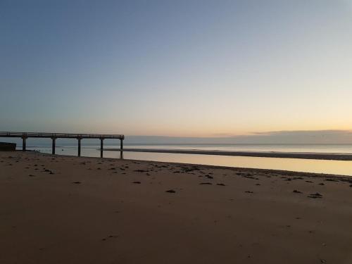 une jetée sur une plage avec l'océan en arrière-plan dans l'établissement Jolie maison en pierre proche de la plage d'Omaha, à Vierville-sur-Mer