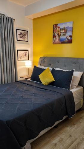 a bedroom with a blue bed with a yellow wall at mesavirre garden residences in Bacolod