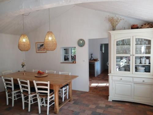 een eetkamer met een houten tafel en stoelen bij L'écrin de la Pinède in La Barre-de-Monts