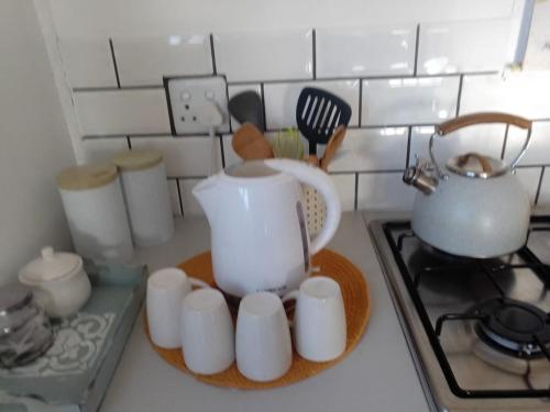 a kitchen counter with a tea pot and white cups at CoCo de Mer Self Catering Log 1 in Lambertʼs Bay